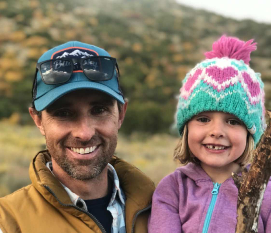 In this heartwarming photo, a father and daughter share joyful smiles while savoring the beauty of the outdoors.